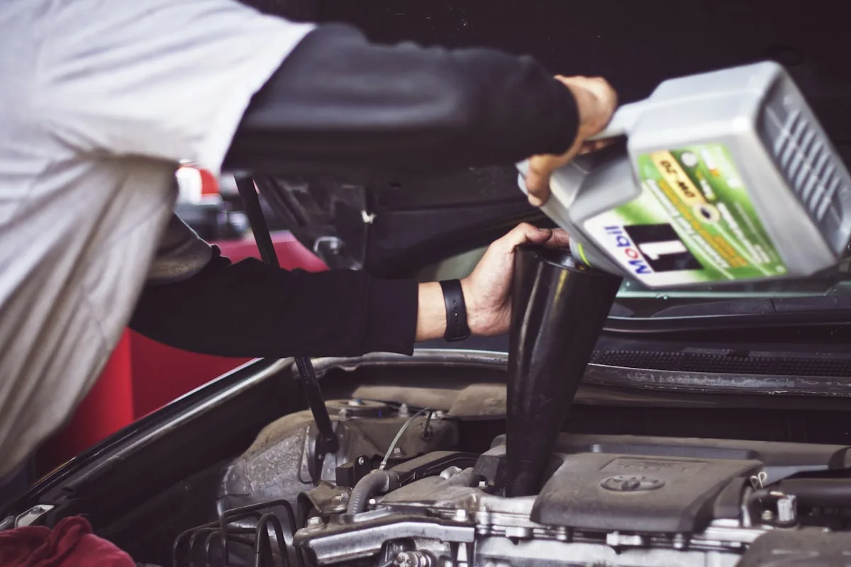 A technician topping up oil on a vehicle